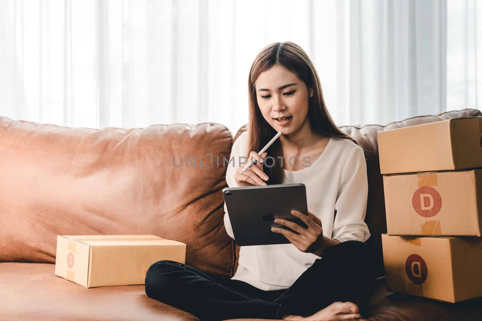 Asian female with small stock business owner holding digital tablet and retail package parcel boxes checking commercial shipping delivery order 