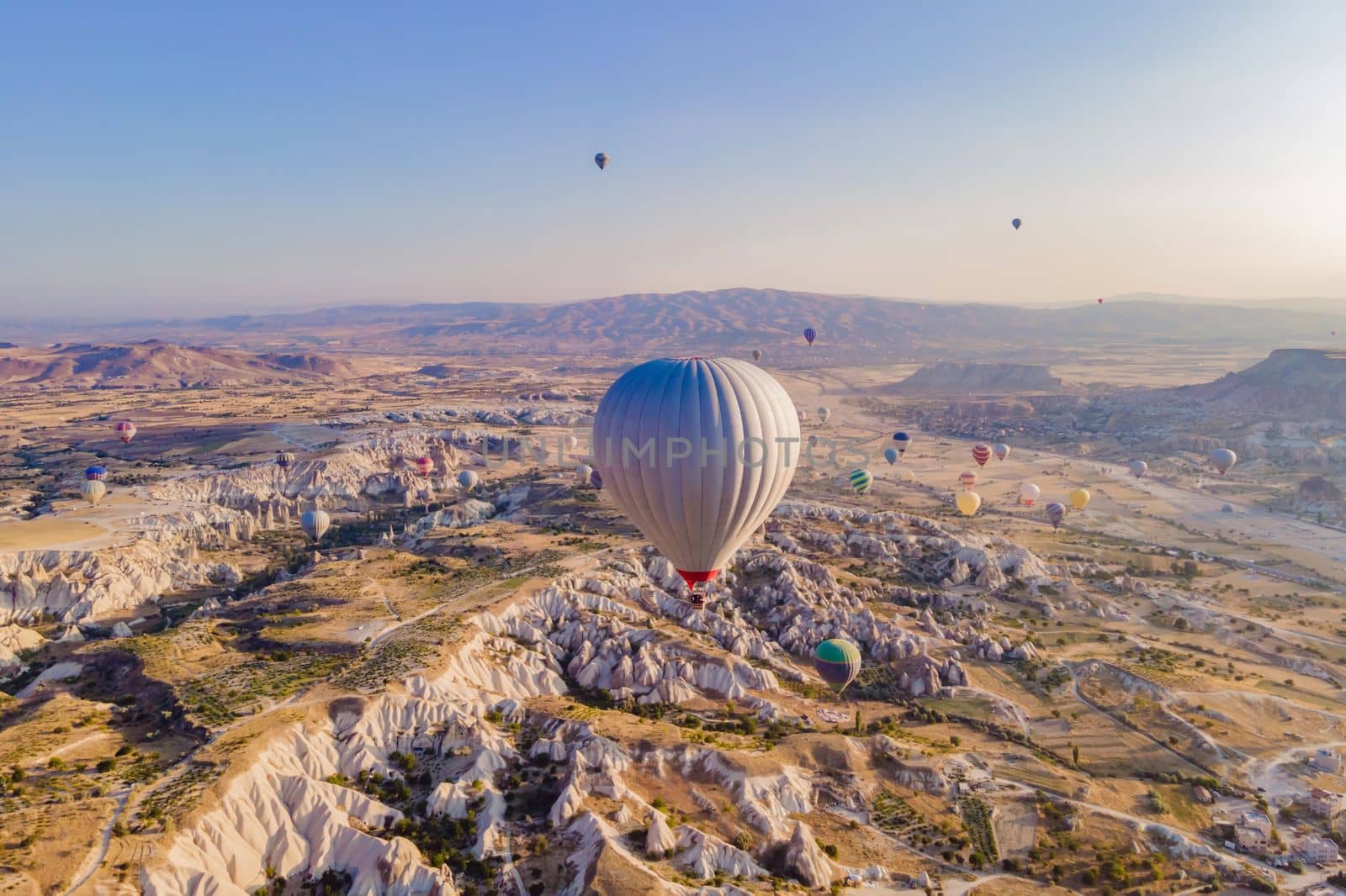 Colorful hot air balloons flying over at fairy chimneys valley in Nevsehir, Goreme, Cappadocia Turkey. Spectacular panoramic drone view of the underground city and ballooning tourism. High quality by galitskaya