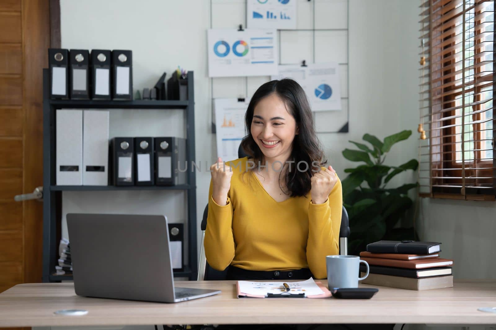 Pretty Asian businesswoman sitting on a laptop And the work came out successfully and the goal was achieved, happy and satisfied with her..