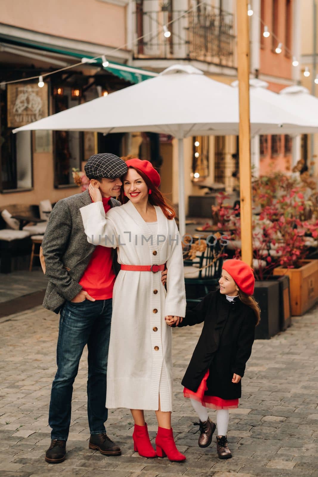 A stylish family of three strolls through the autumn city posing for a photographer . Dad, mom and daughter in the autumn city.