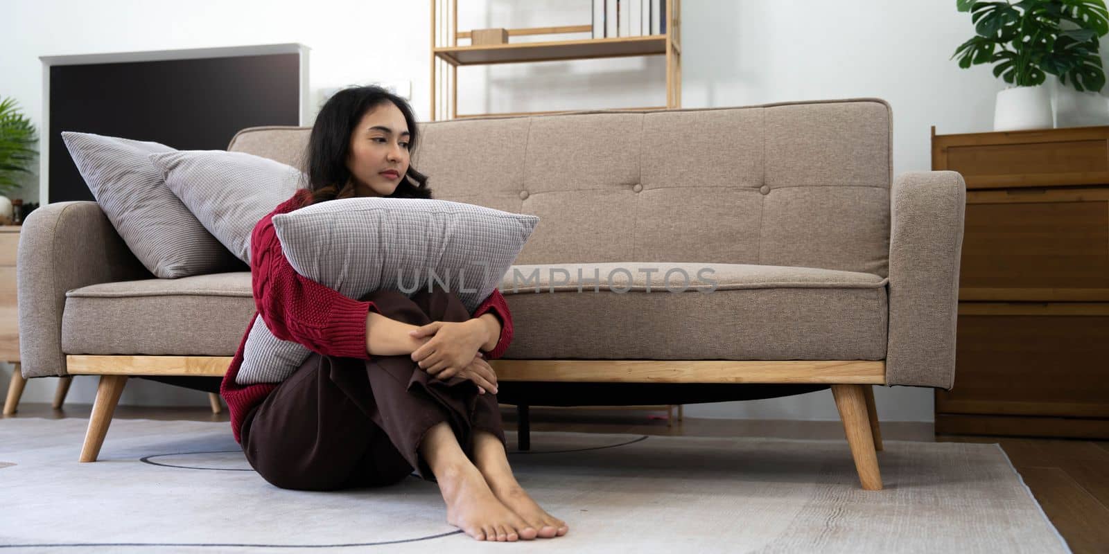 Unhappy asian pretty young woman siting alone on couch with feeling sadness.