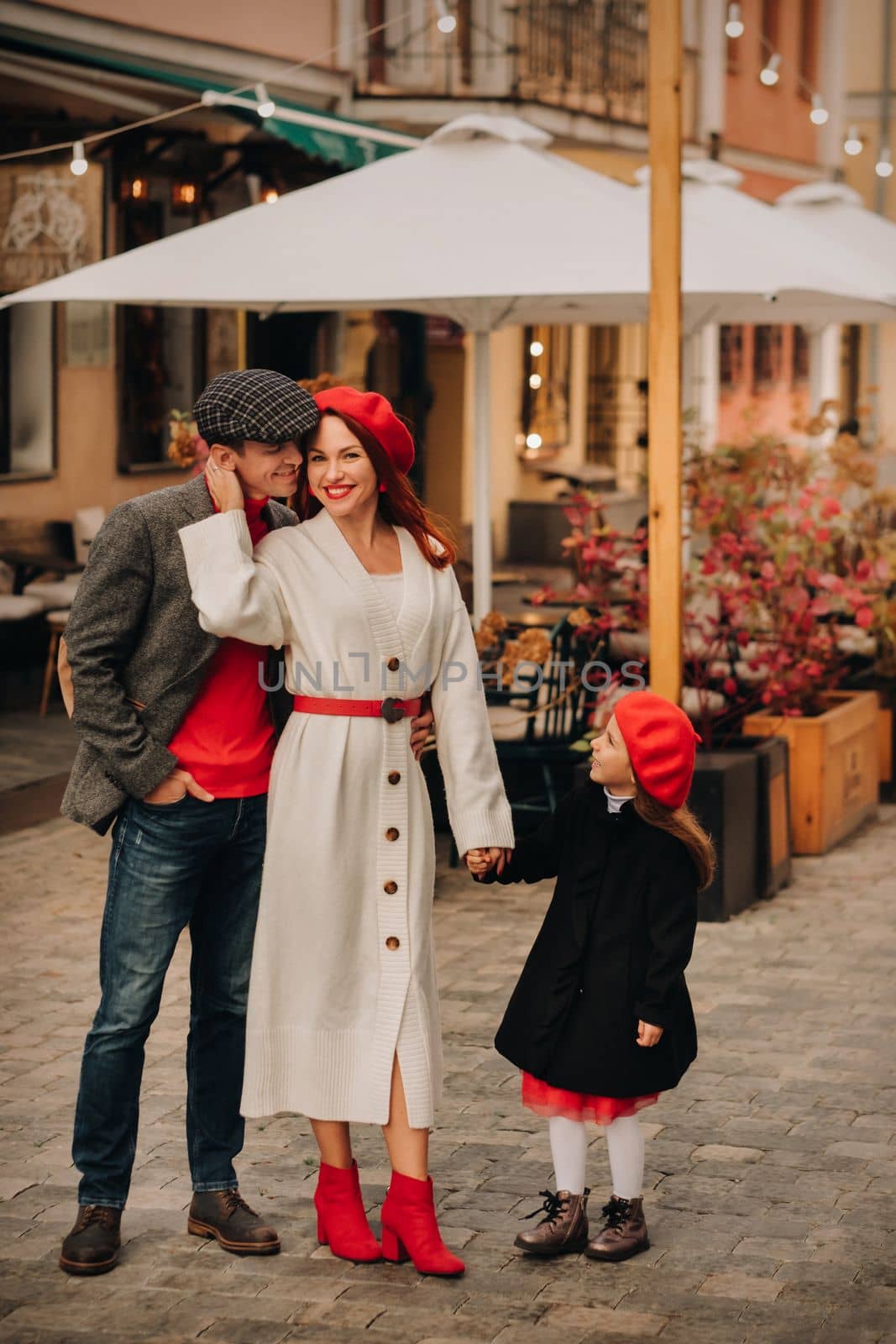 A stylish family of three strolls through the autumn city posing for a photographer . Dad, mom and daughter in the autumn city.