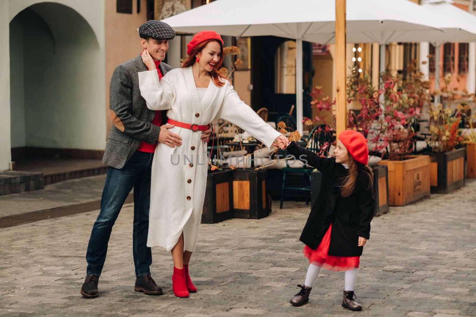 A stylish family of three strolls through the autumn city posing for a photographer . Dad, mom and daughter in the autumn city.