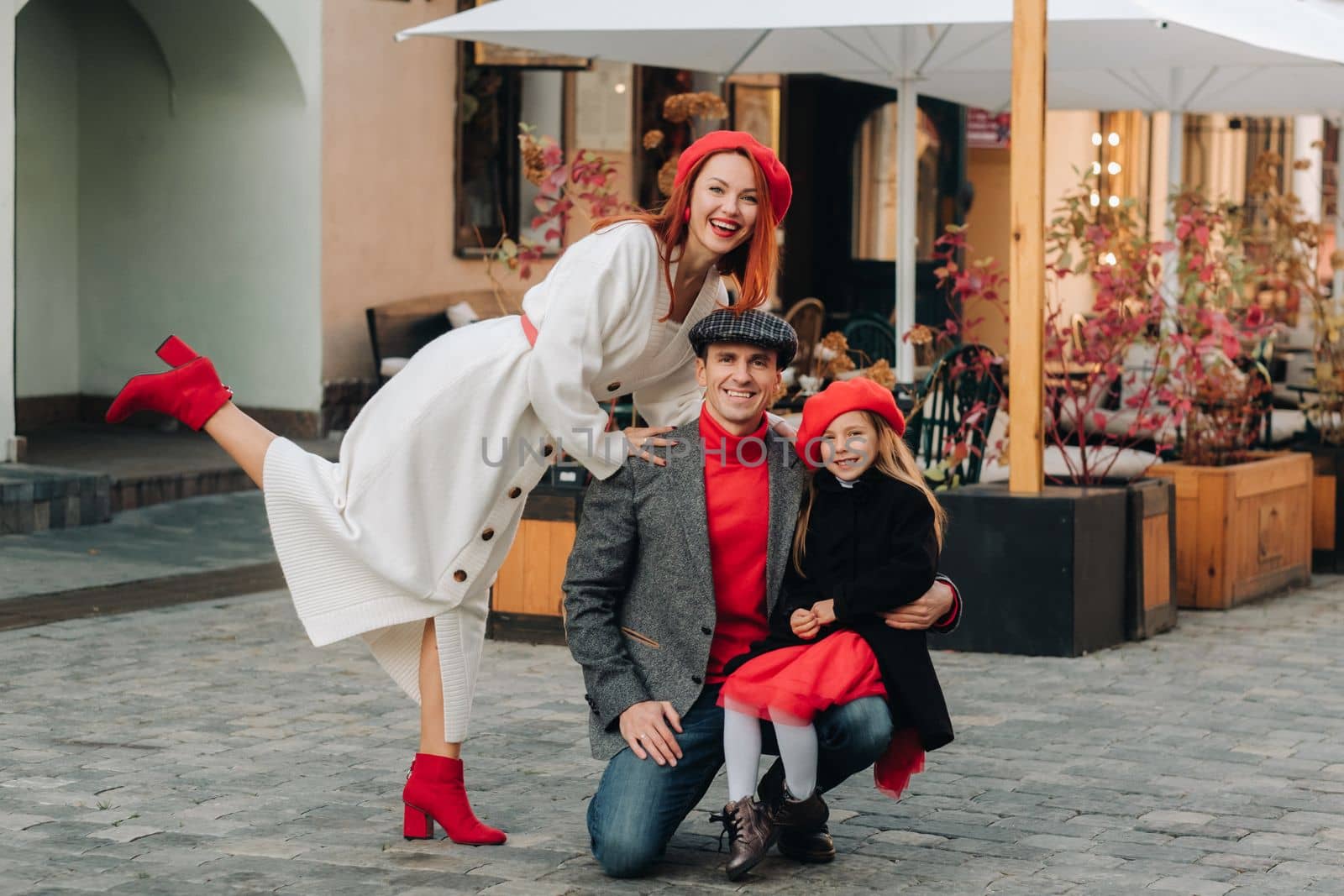 A stylish family of three strolls through the autumn city posing for a photographer . Dad, mom and daughter in the autumn city by Lobachad