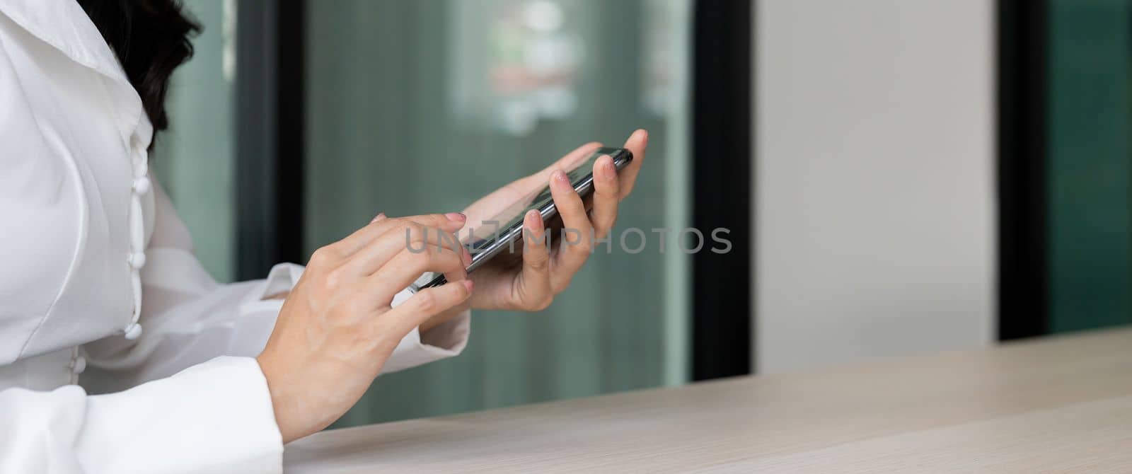 Woman with a finger on the screen using a mobile phone in the office.