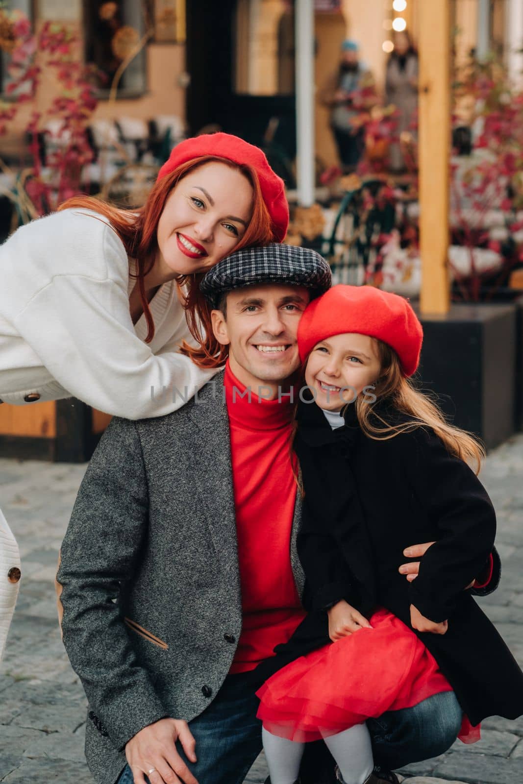 A stylish family of three strolls through the autumn city posing for a photographer . Dad, mom and daughter in the autumn city by Lobachad