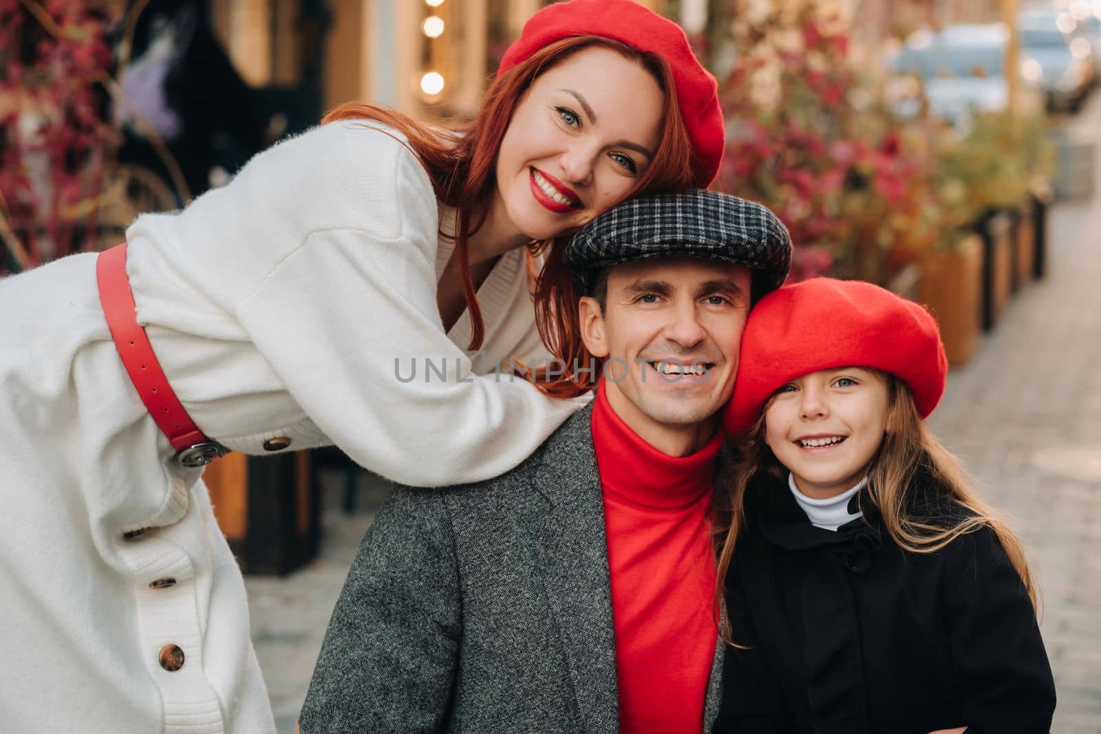 A stylish family of three strolls through the autumn city posing for a photographer . Dad, mom and daughter in the autumn city.