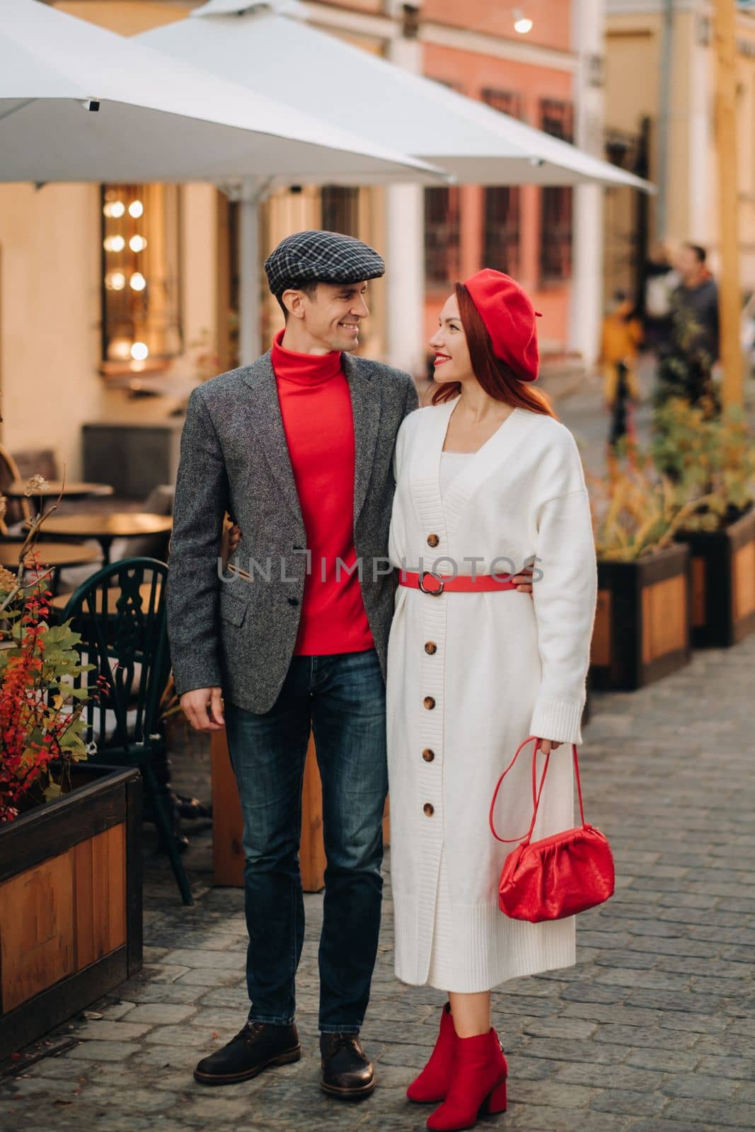 Portrait of a happy couple walking on the street in an autumn city. Stylish couple in retro style in autumn in the city by Lobachad