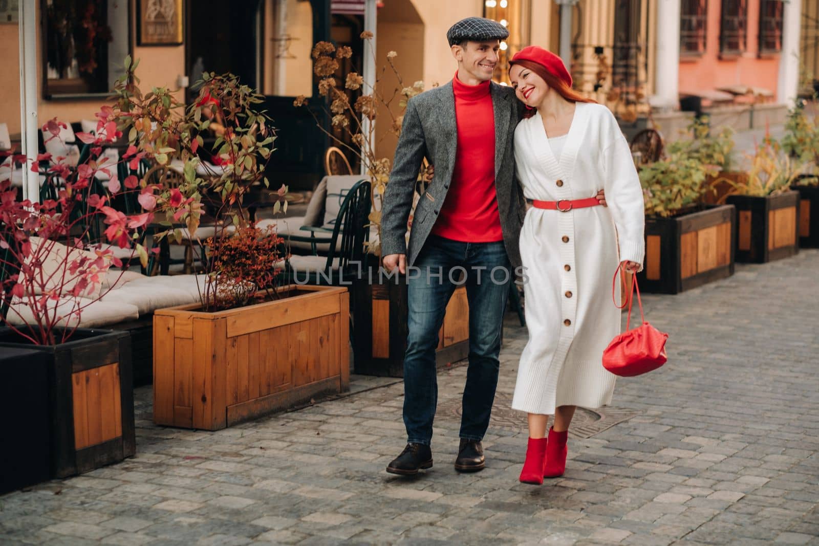 Portrait of a happy couple walking on the street in an autumn city. Stylish couple in retro style in autumn in the city.