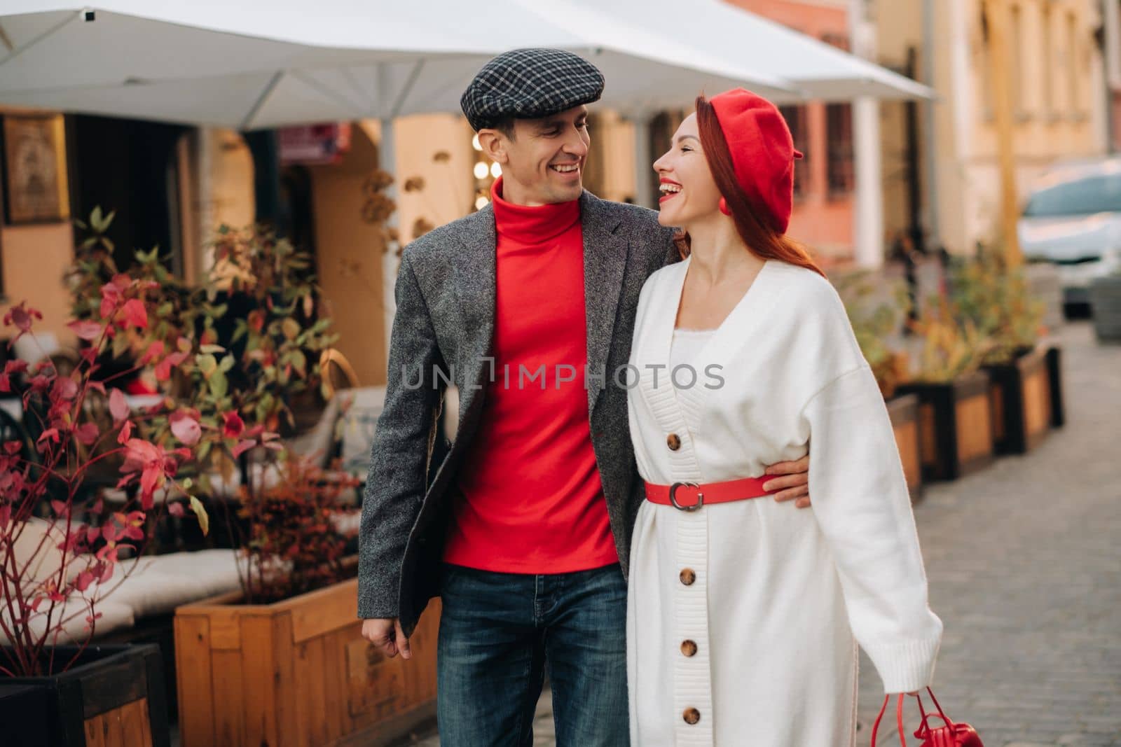 Portrait of a happy couple walking on the street in an autumn city. Stylish couple in retro style in autumn in the city by Lobachad