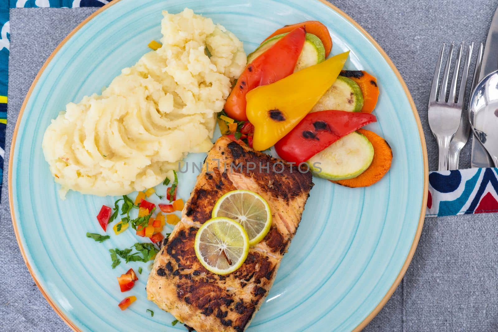 Salmon steak a la carte meal with vegetables and mashed potato at restaurant table setting