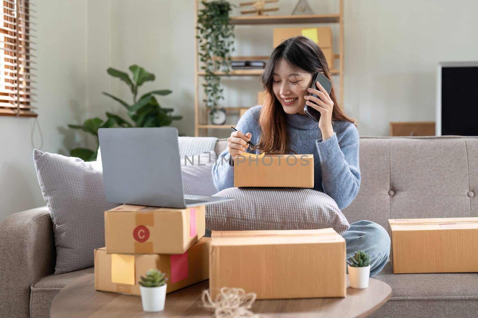 Small business entrepreneur SME freelance woman using phone call receive from customer checking product on stock at home office, online marketing packaging delivery box, SME e-commerce concept.