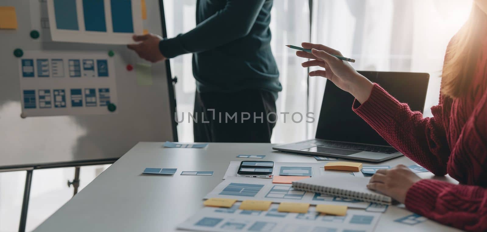 Ux developer and ui designer brainstorming about mobile app interface wireframe design on table with customer breif and color code at modern office.