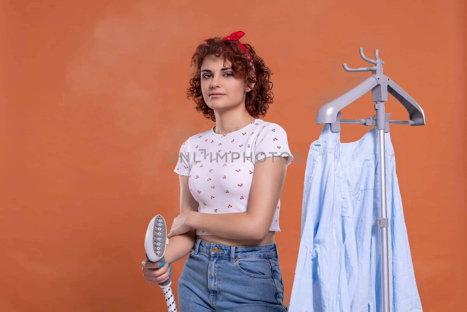 Hot steam used for ironing clothes. Steam device. An ironing steamer used by a young woman.