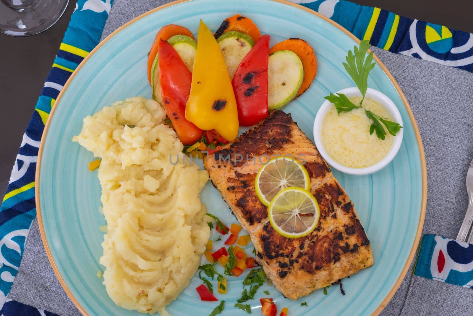 Salmon steak a la carte meal with tartar sauce dip vegetables and mashed potato at restaurant table setting