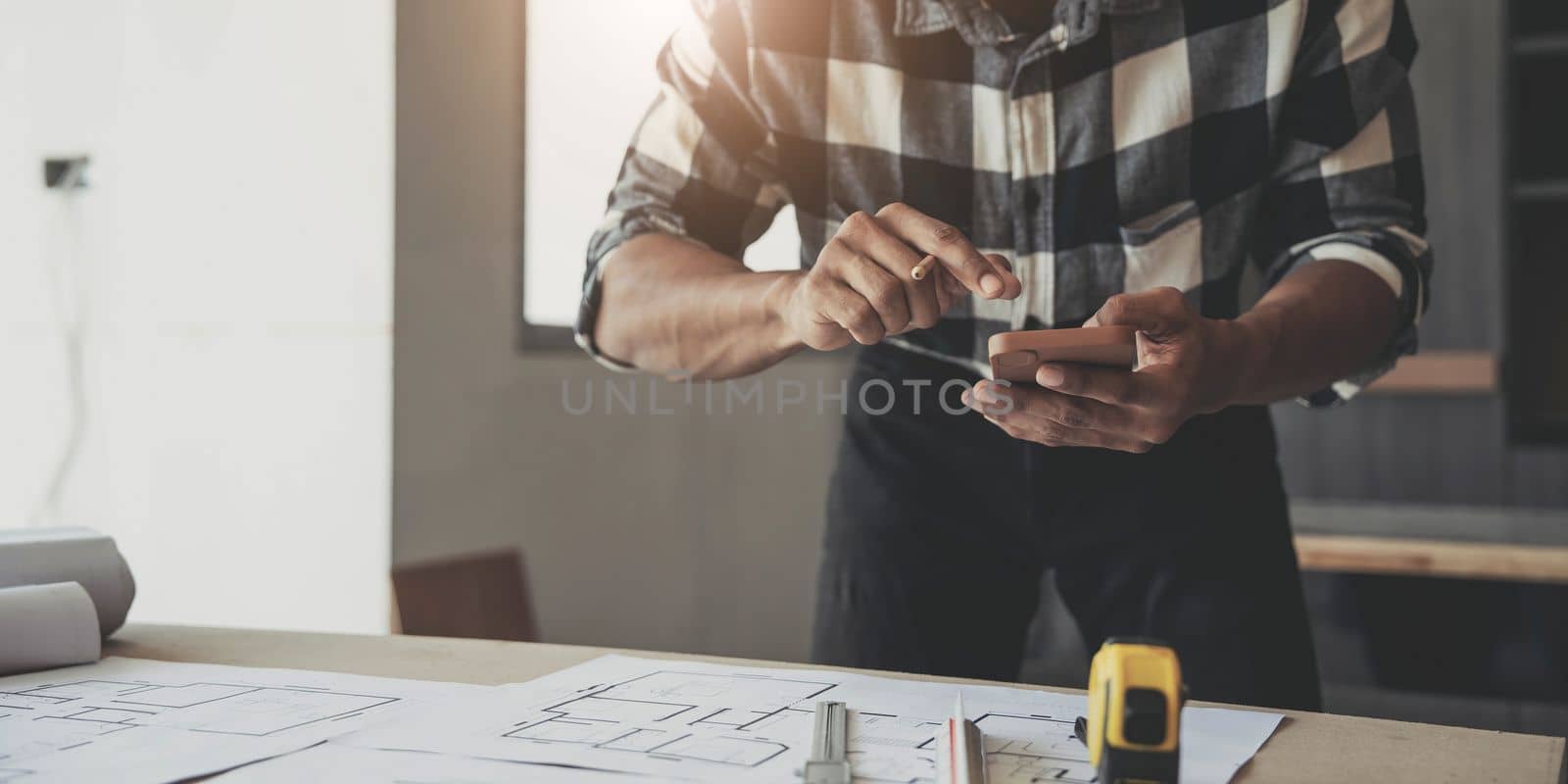 Image of engineer drawing a blue print design building or house, An engineer workplace with blueprints, pencil, protractor and safety helmet, Industry concept..