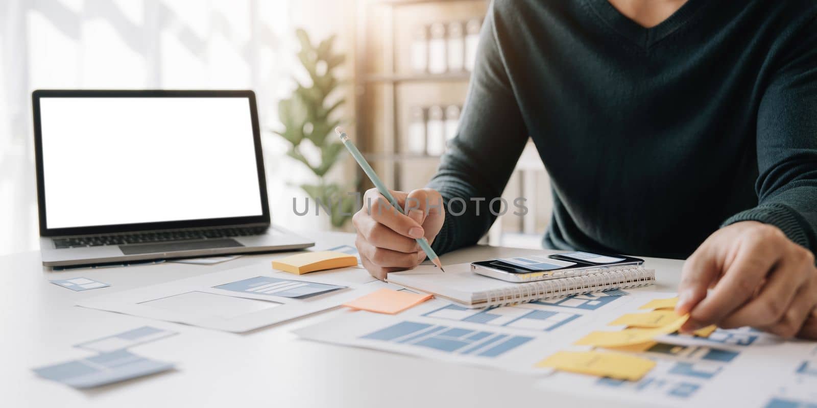 Asian man enjoying on media paperwork design with other office suppliers over sticky notes on the whiteboard. Creative digital development concept. by wichayada