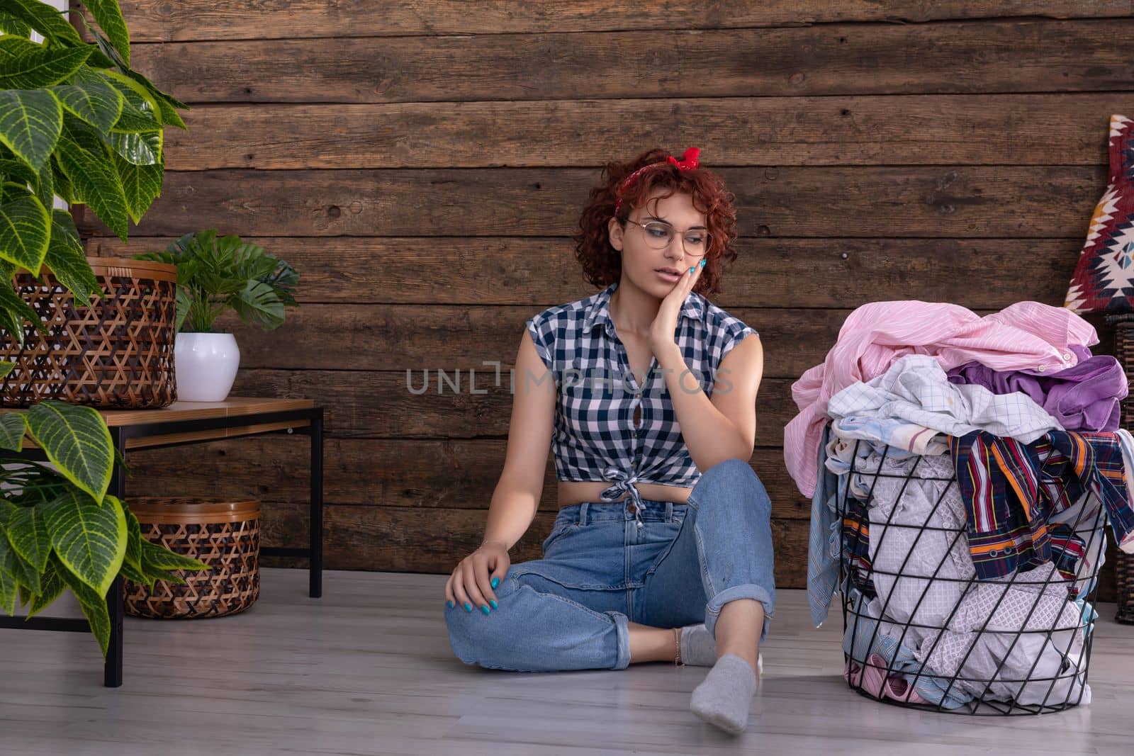 Short curly dark-colored hair. The surprised girl sees on the floor and is surprised by the large amount of wet laundry to be hung up.