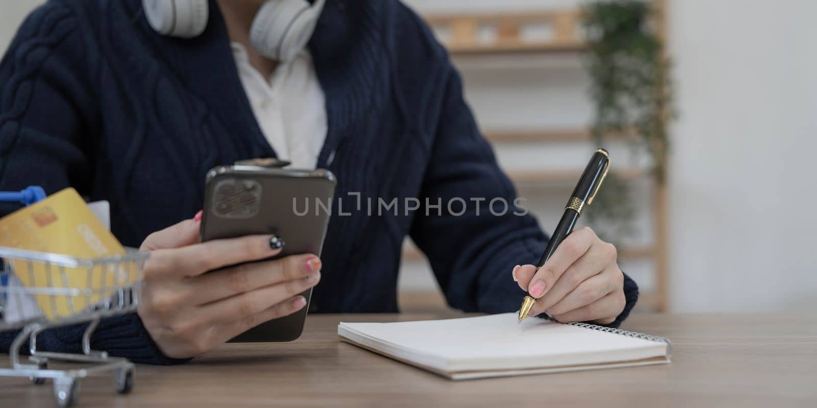 women use mobile phones and take notes on their notebooks while working on laptop computers, online business,work from home, teleworking concept. by wichayada