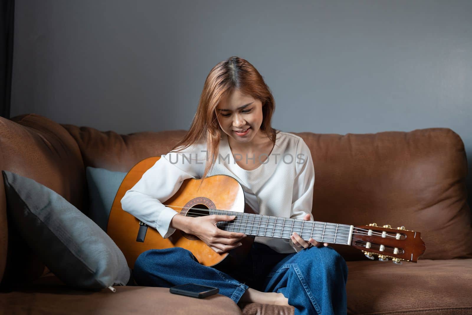 Image of happy beautiful woman playing guitar and composing song. by nateemee