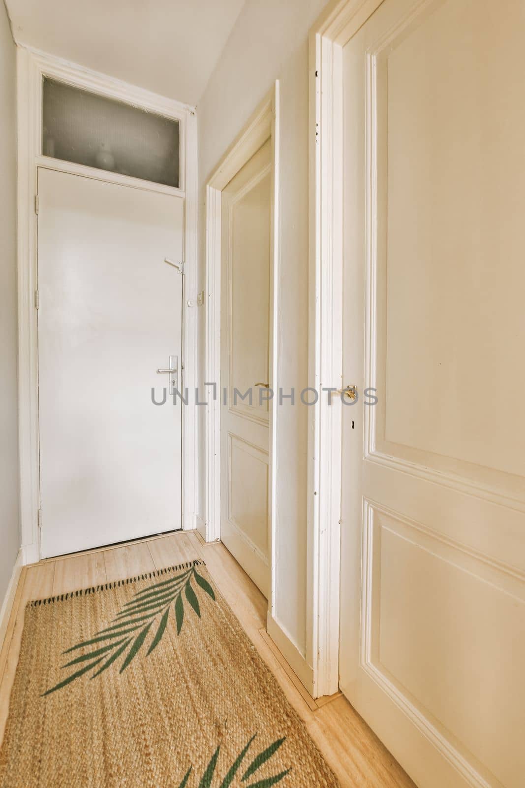 an empty room with wooden floors and white doors on either side, there is a door in the corner that leads to another room