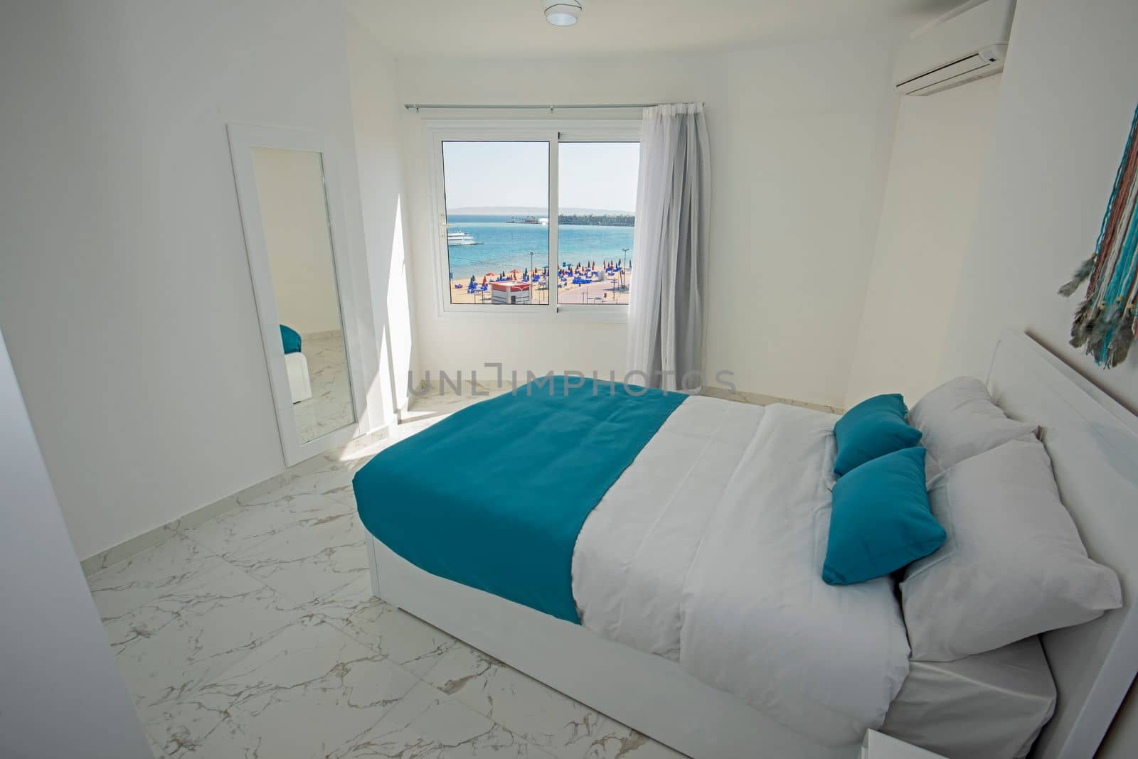 Interior design decor furnishing of luxury show home bedroom showing furniture and double bed in resort with sea view from window