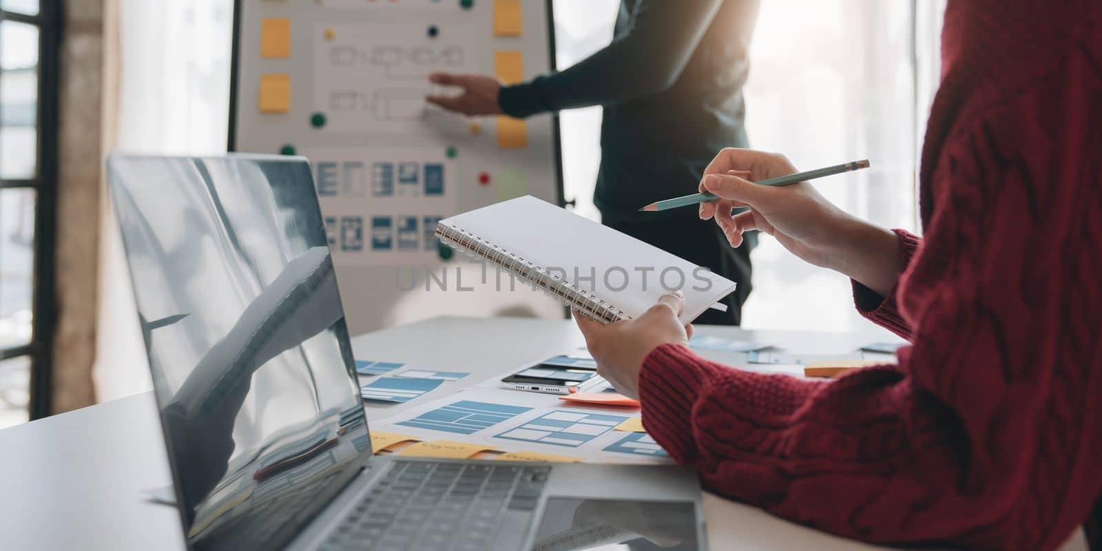 Ux developer and ui designer brainstorming about mobile app interface wireframe design on table with customer breif and color code at modern office.