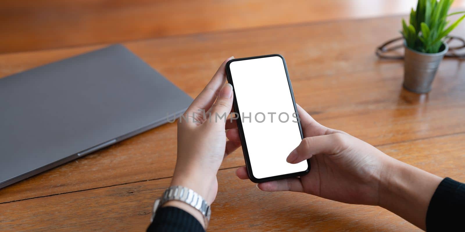 Woman hand holding smartphone with blur bokeh. Blank screen mobile phone for graphic display montage..