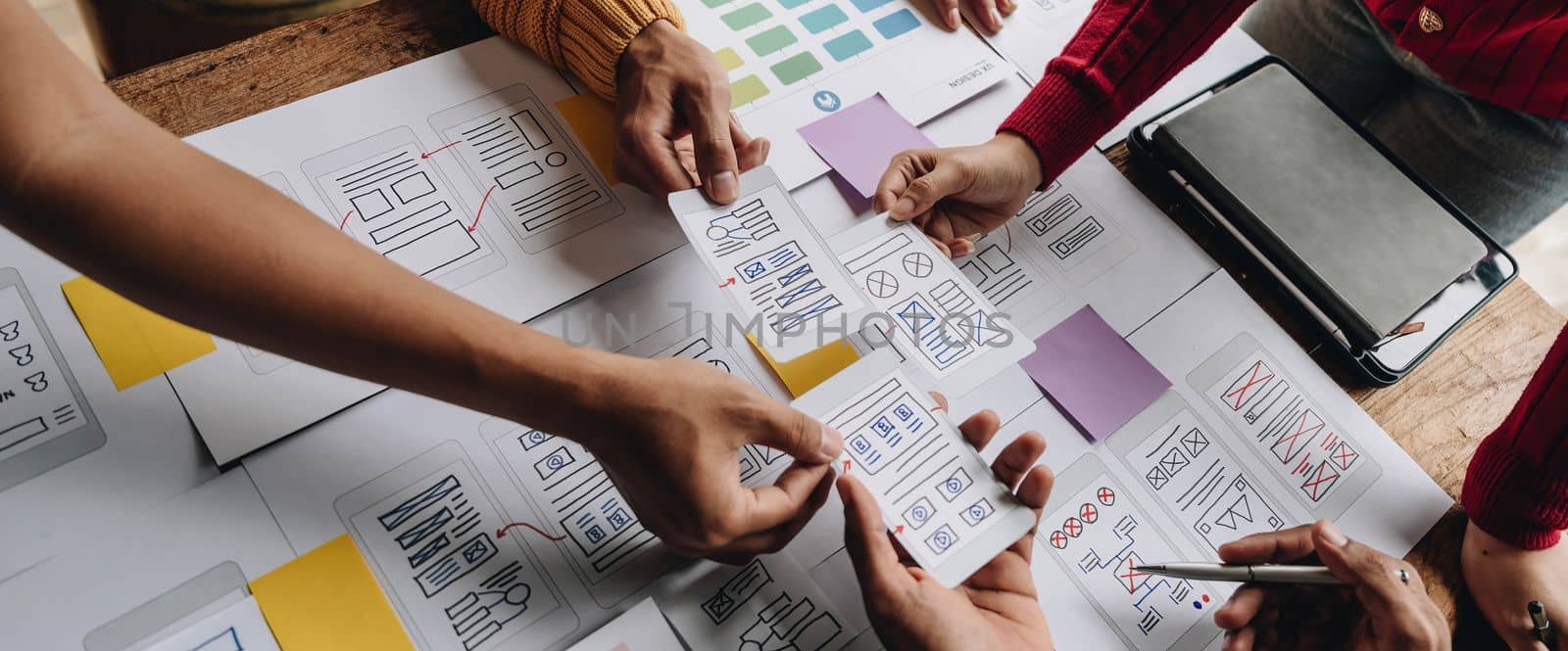UI UX creative designer team designing wireframe layout for responsive mobile smartphone application in office.