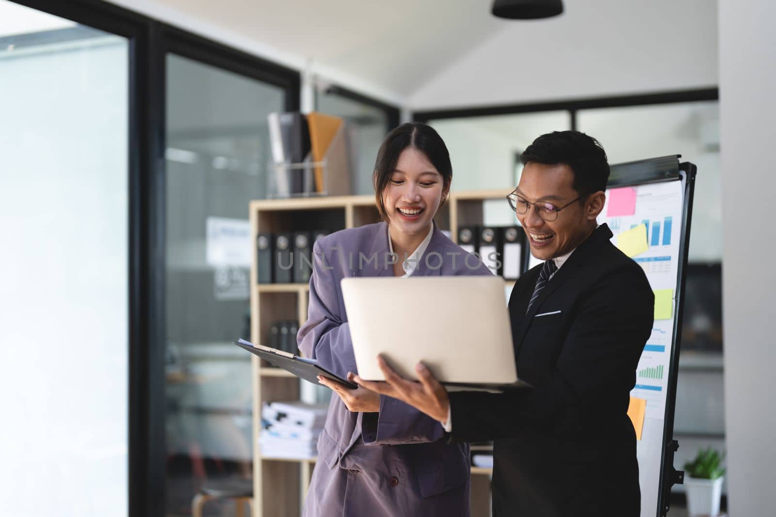 business people meet and discuss chart and point at chart Company report share marketing in the office. Business team stand to discuss and work together at the office.