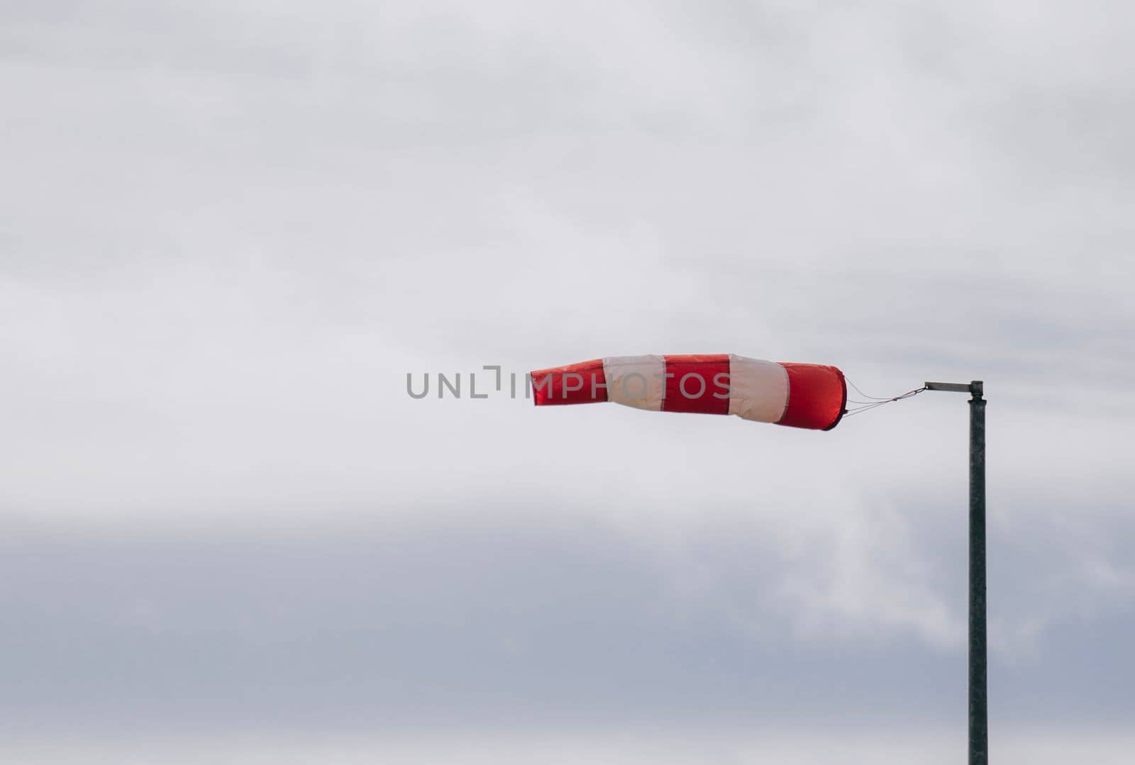 Frayed windsock in moderate wind against blue sky with copy space