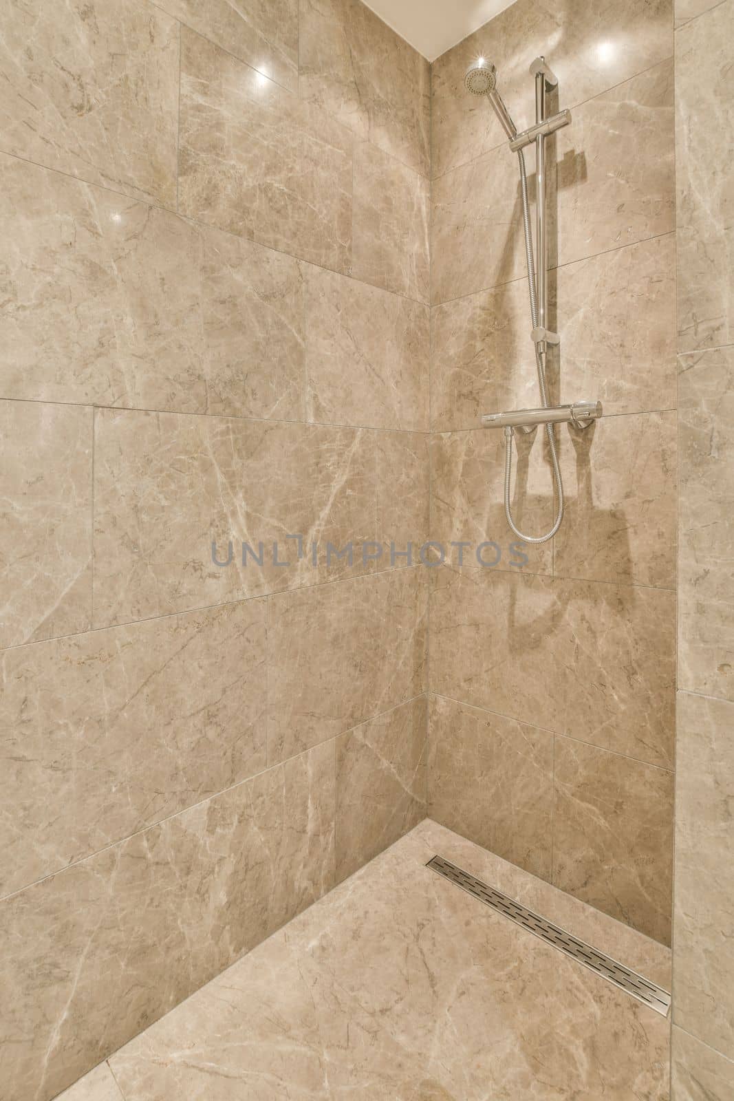 a bathroom with marble walls and shower head mounted to the wall, it's not clear in this photo