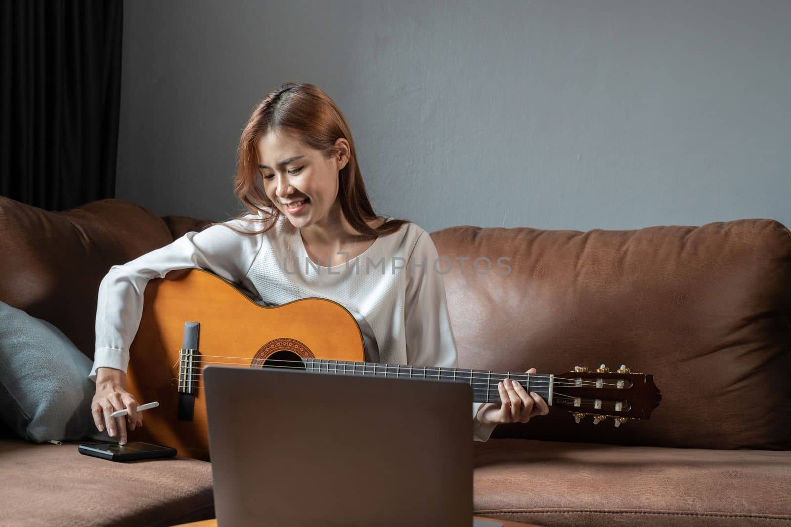 Image of happy beautiful woman playing guitar and composing song.