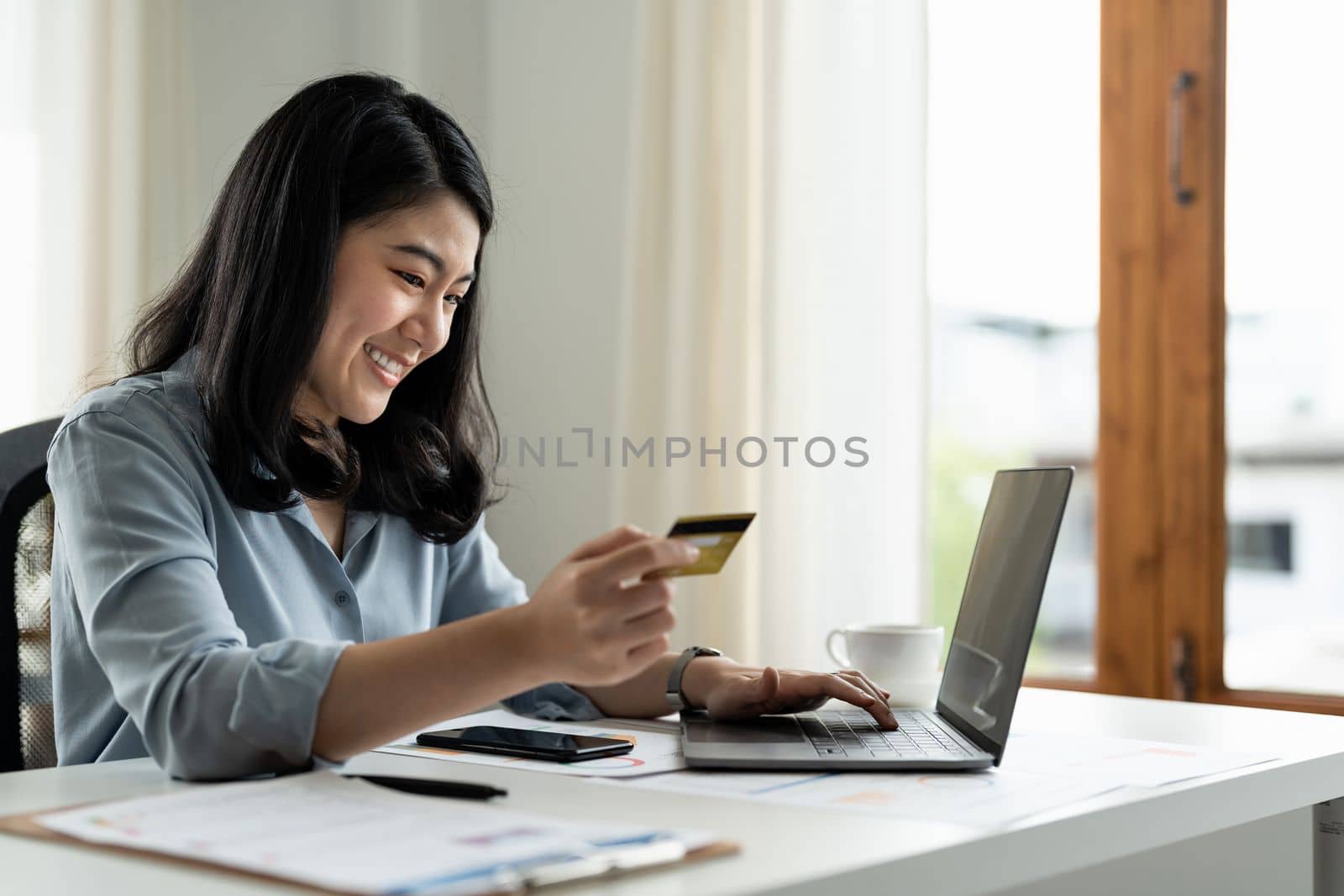 Asian business woman holding credit card and typing on laptop for online shopping and payment makes a purchase on the Internet, Online payment, Business financial and technology concept.