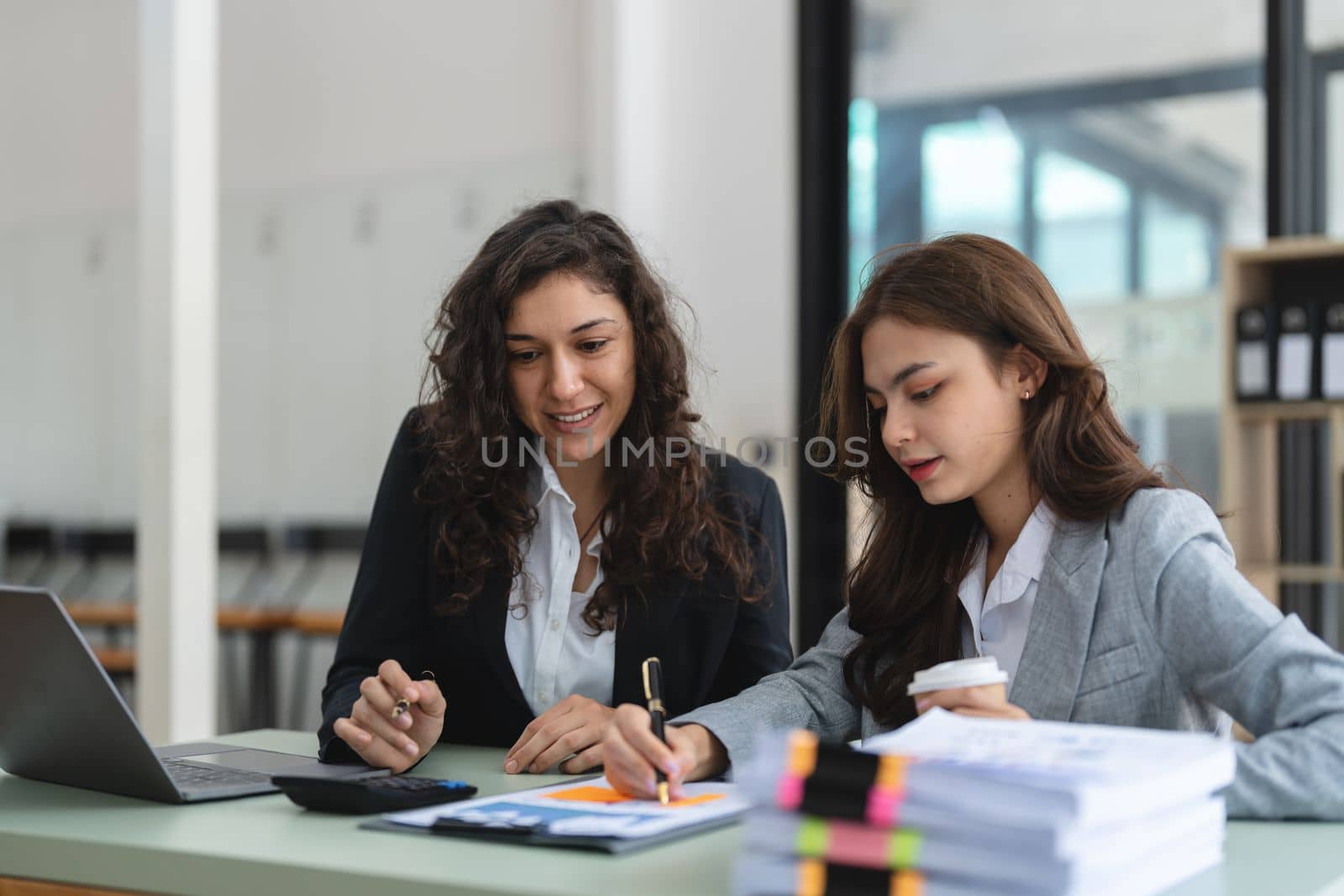 Diverse businesspeople cooperate work together discussing company financial statistics, multiracial colleagues collaborate brainstorm with finance on tablet