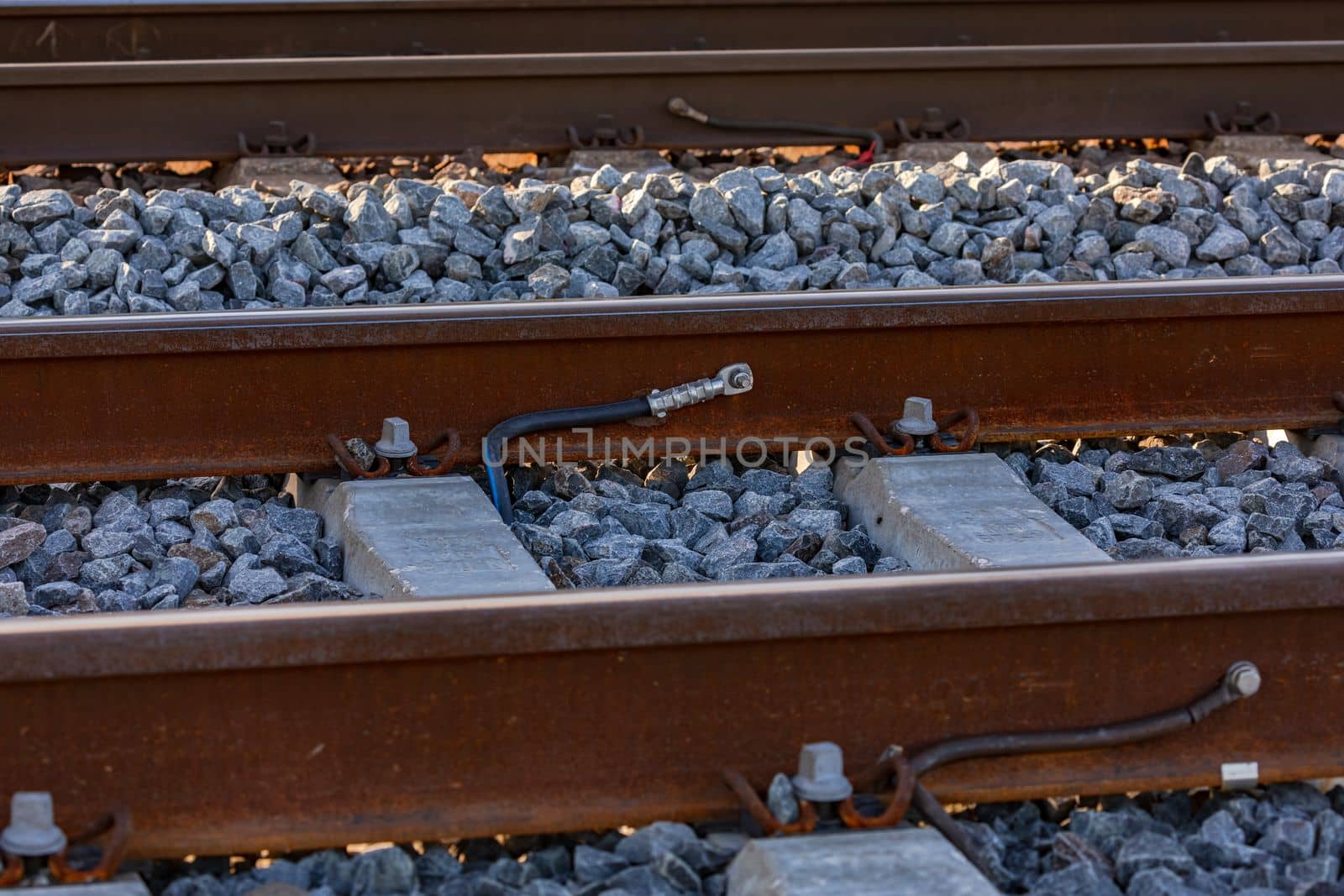 Cable lugs on a rail on a railroad track in a ballast bed