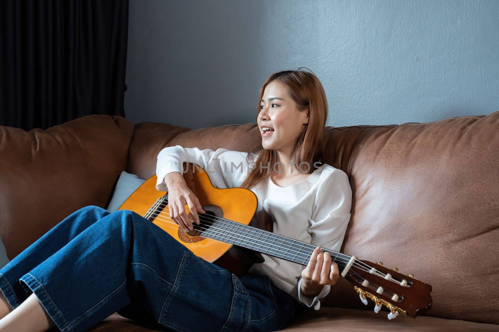 Image of happy beautiful woman playing guitar and composing song by nateemee