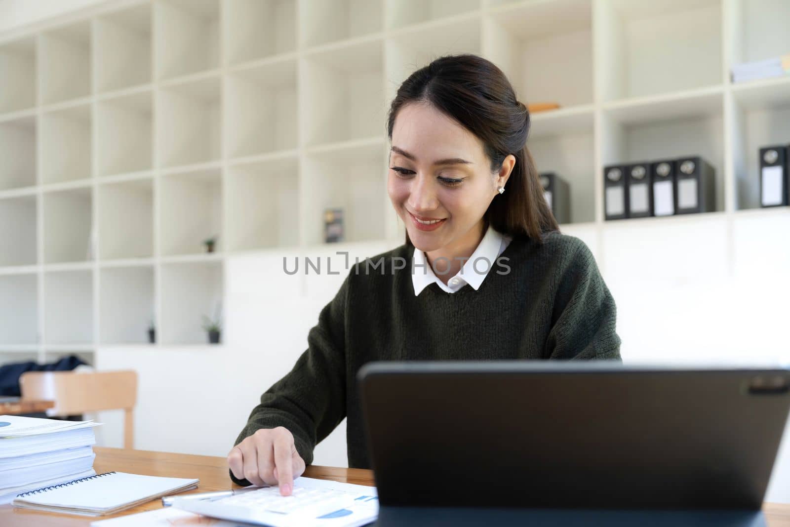 Portrait of an Asian young business Female working on a laptop computer in her workstation.Business people employee freelance online report marketing e-commerce telemarketing concept. by wichayada