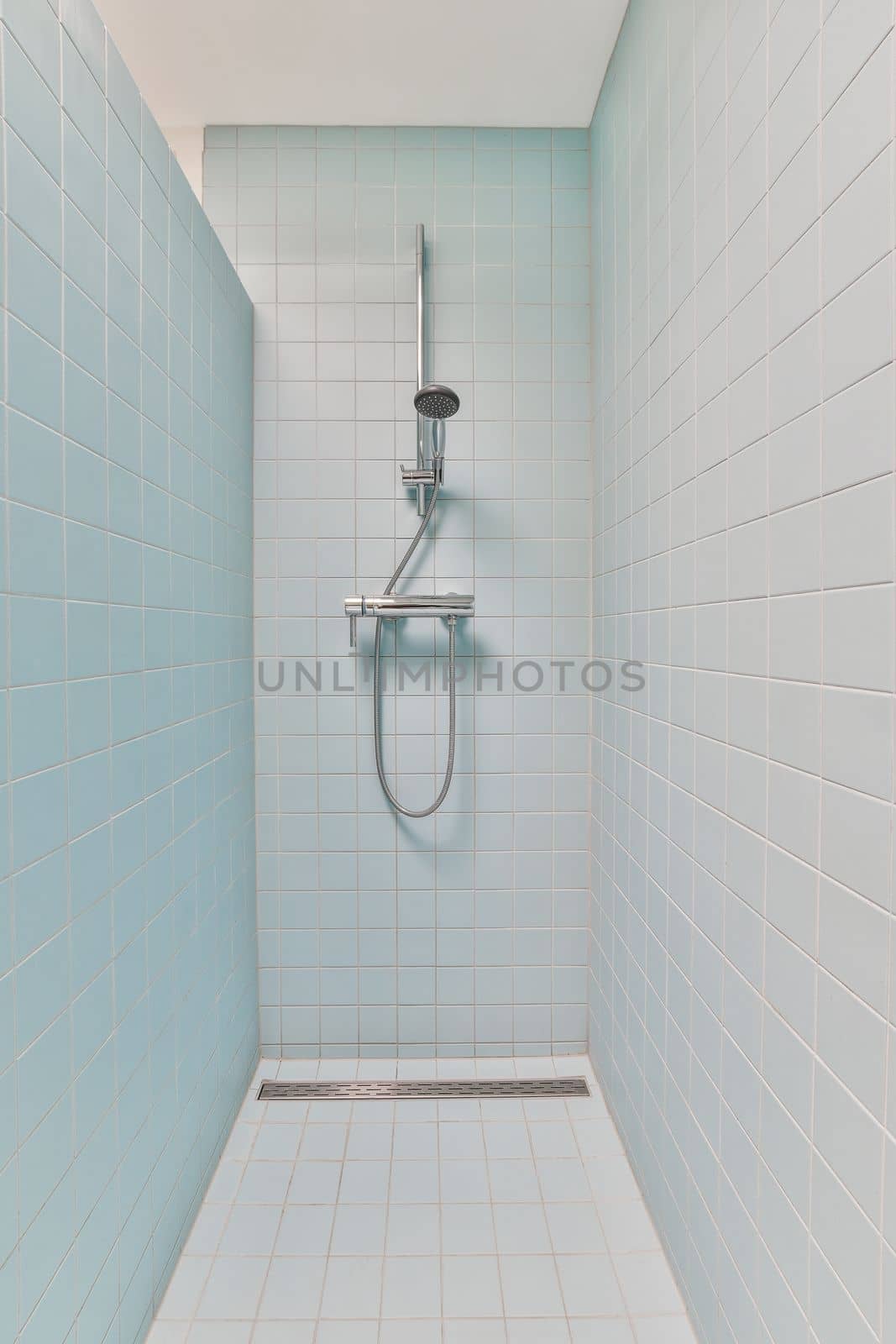 a shower room with blue tiles on the walls and white tile flooring around the bathtub, which is also used as a