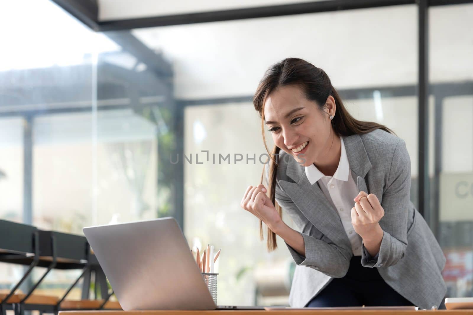 Excited happy Asian woman looking at the phone screen, celebrating an online win, overjoyed young asian female screaming with joy, isolated over a white blur background.