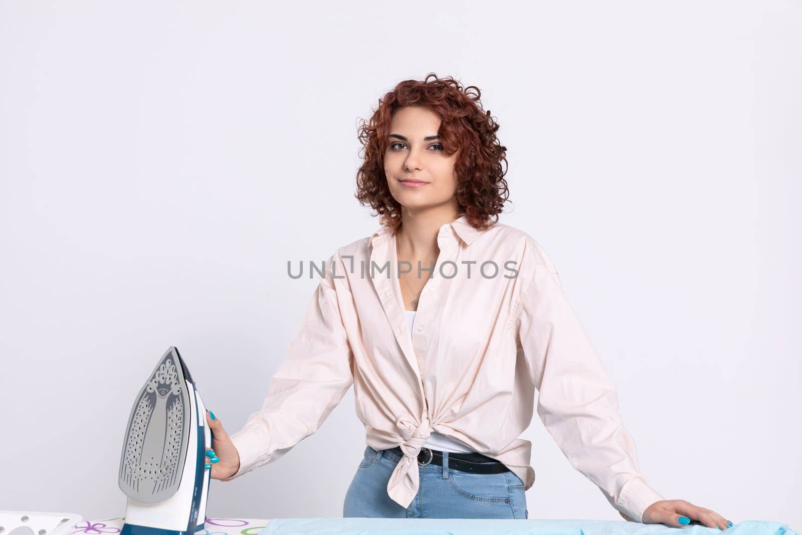 A girl with curly hair and a gentle smile on her face ready to start the daily ritual of ironing shirts. Natural hairstyle.