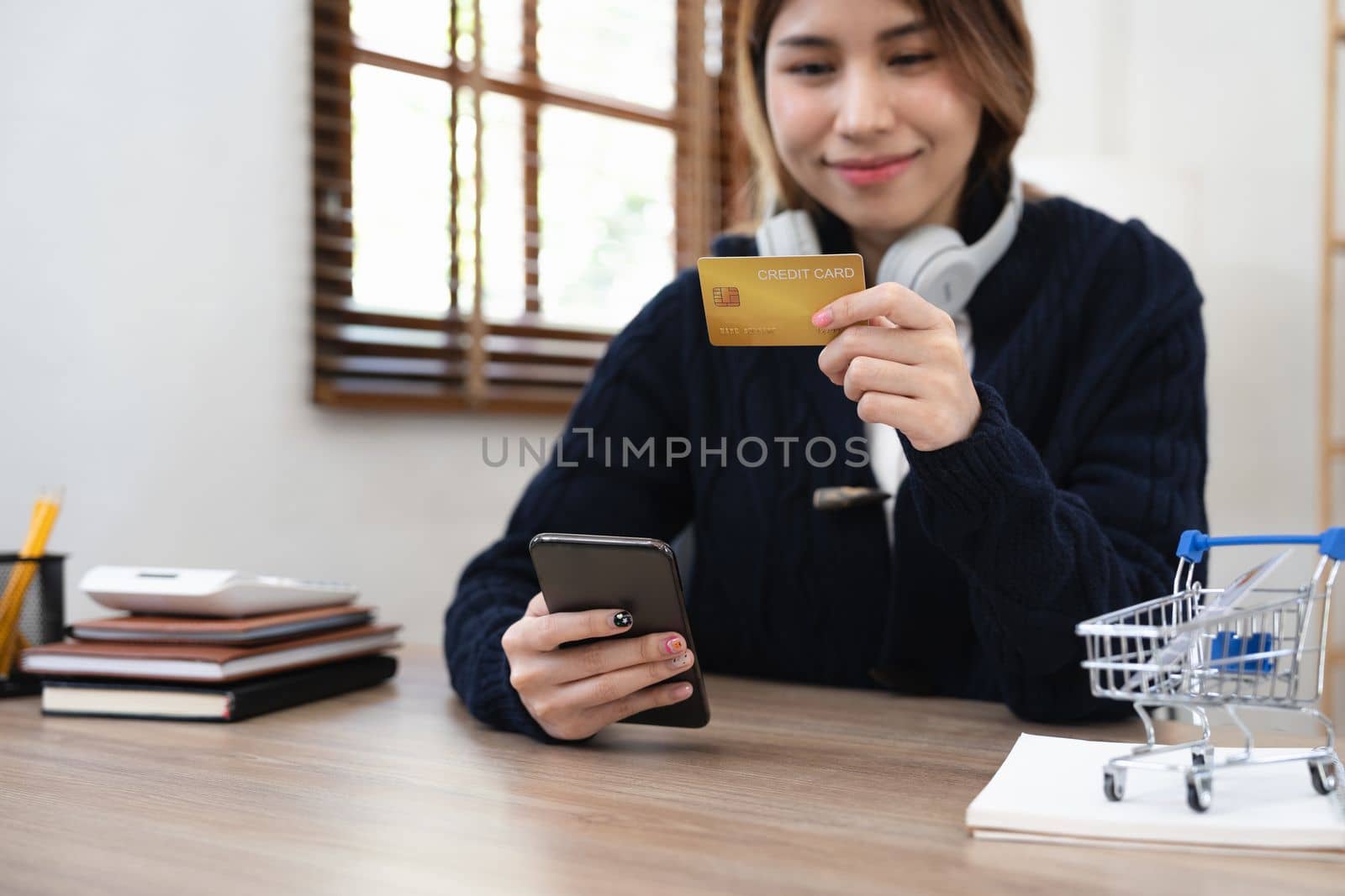 Asian girl making online payment using mobile phone for shopping at home