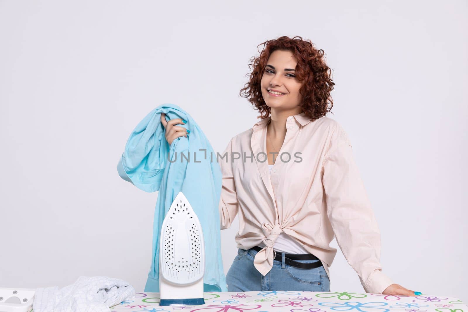 Satisfied young girl before starting ironing with iron. The girl likes to iron shirts. Daily chores at home.
