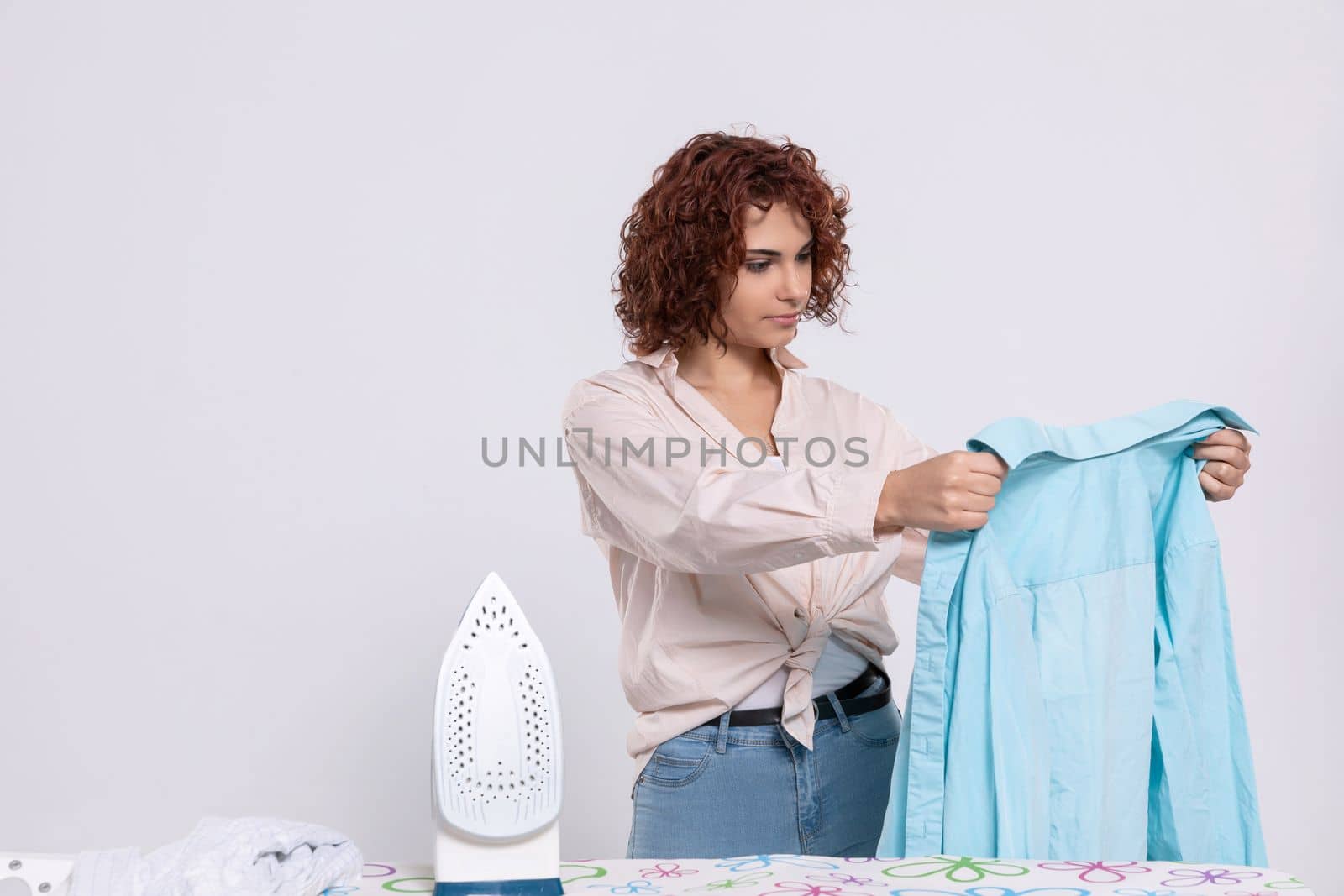 Before ironing, the girl checks the shirt to see if it is thoroughly washed. She inspects whether the shirt has any damage.