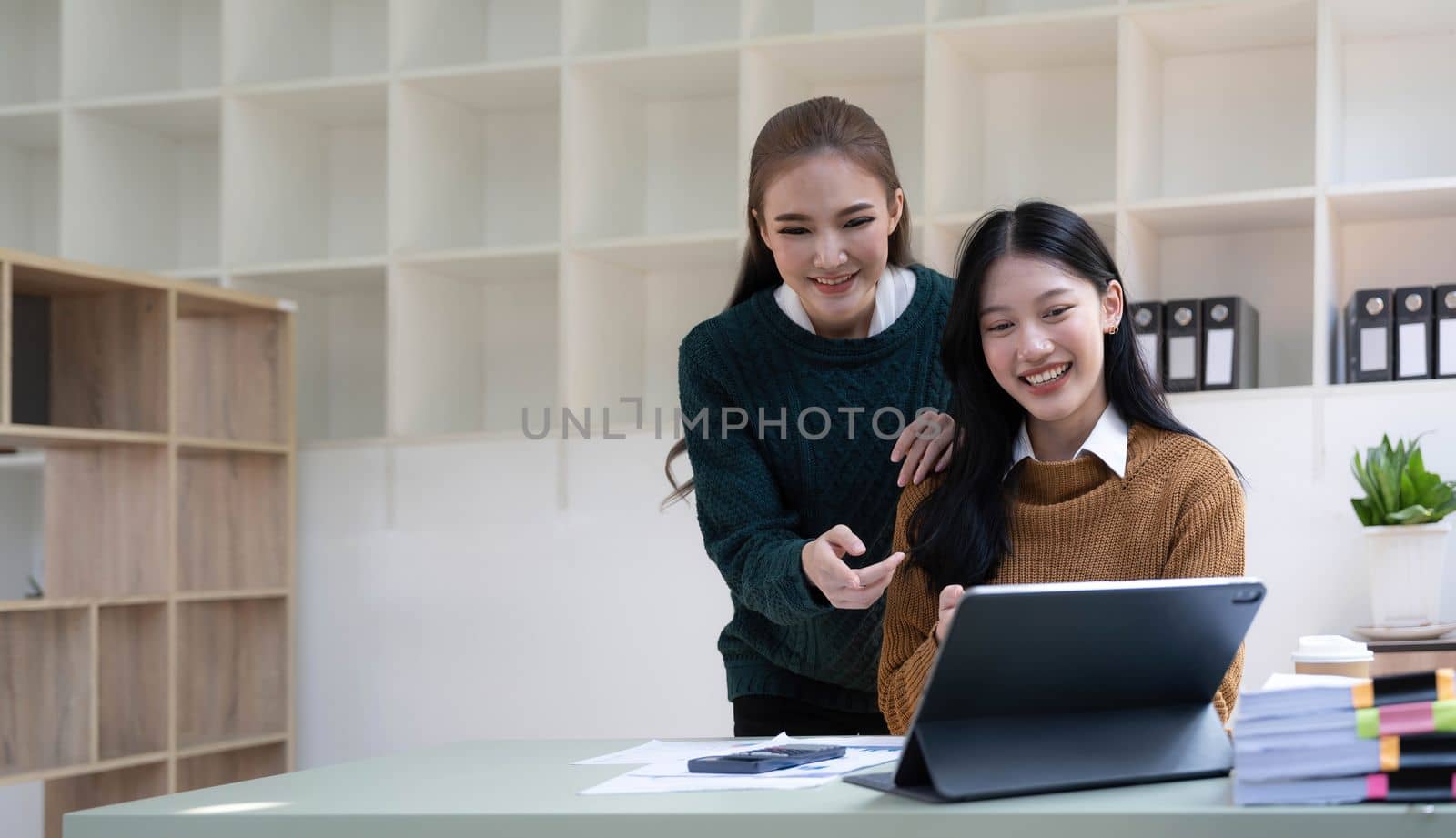 Two young Asian business woman talk, consult, discuss working with new startup project idea presentation analyze plan marketing and investment in the office...