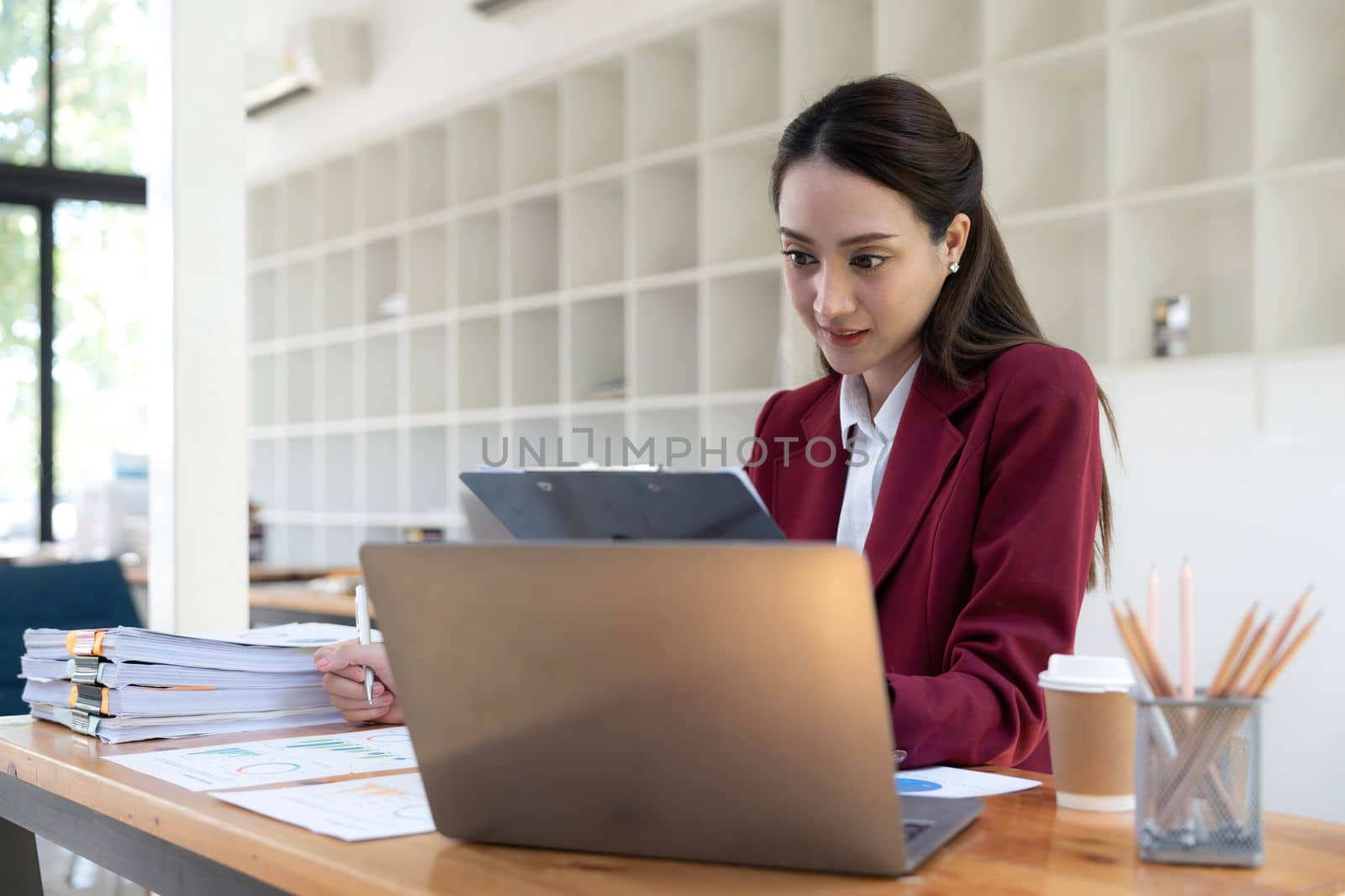 Asian Business woman using calculator and laptop for doing math finance on an office desk, tax, report, accounting, statistics, and analytical research concept.