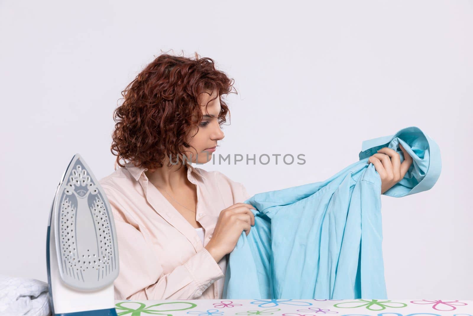 Before ironing, the girl checks the shirt to see if it is thoroughly washed. She inspects whether the shirt has any damage.