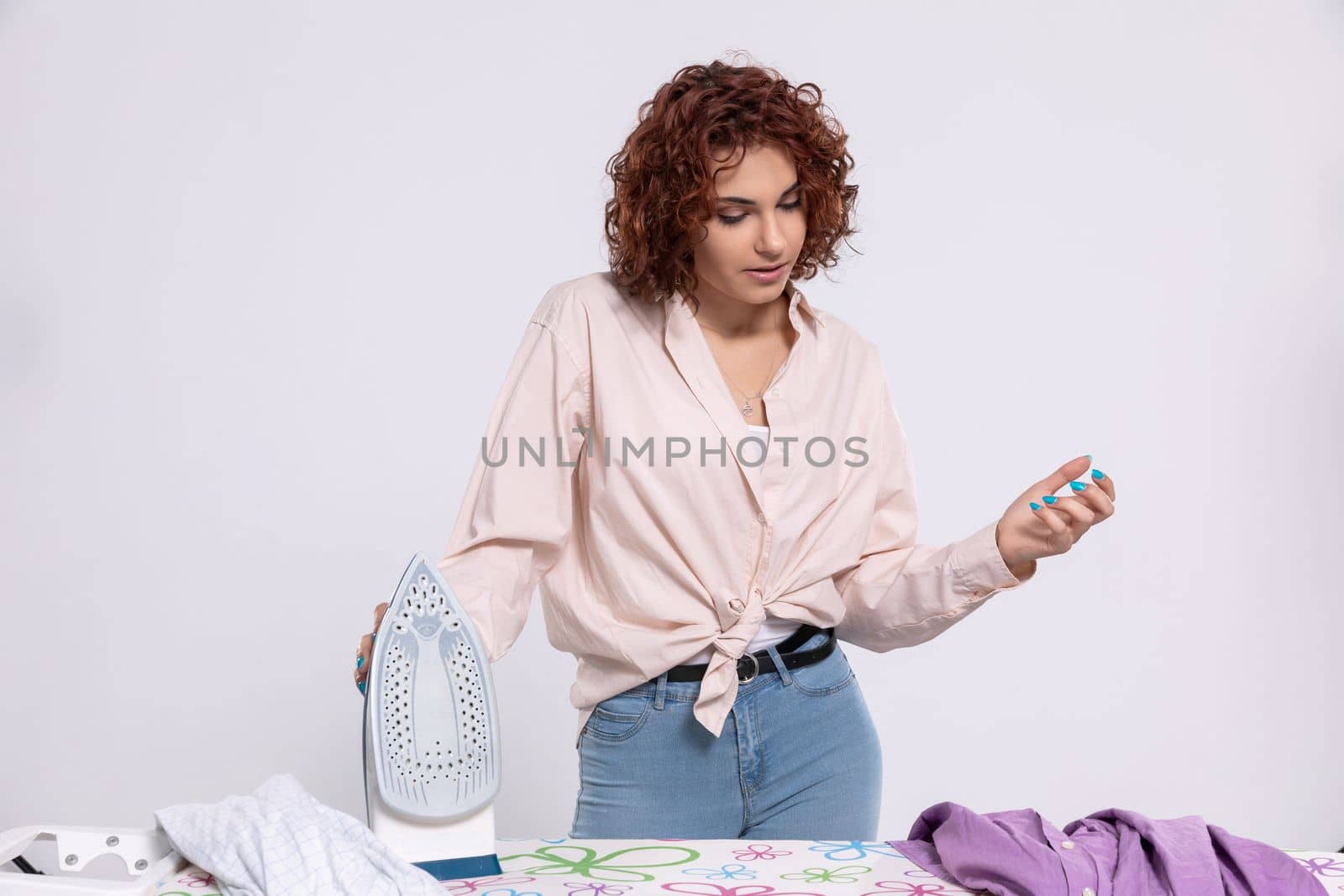 The woman stood over the ironing board and thinks where to start in order to get this job done as quickly as possible. Lots of clothes to iron.