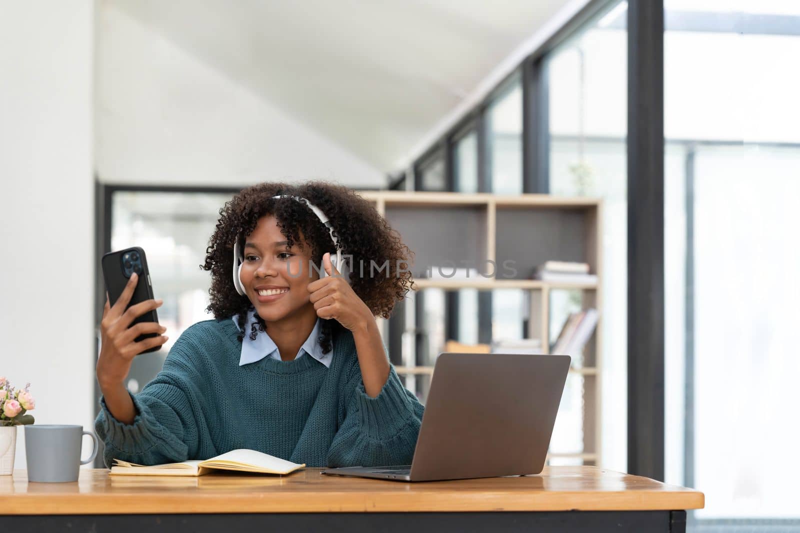 Photo of cheerful joyful woman playing games and wearing wireless headphones at home Play game on your smartphone that wins the moment of victory. Fun and enjoyable vacation.