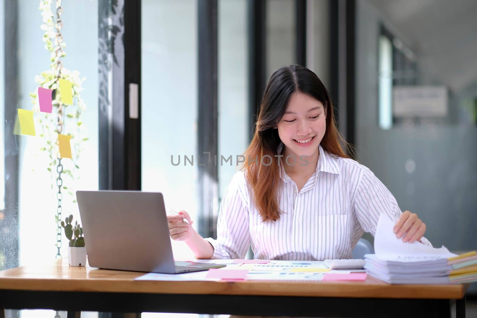 Smiling Young Asian Business women working with calculator, business document and laptop computer notebook,financial inspector and secretary making report,Internal Revenue Service checking document..